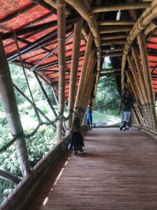 three people standing on a bridge made of giant bamboo polls