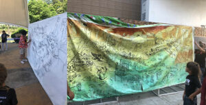 a before and after shot of the collaboratively made mural "greens against the war machine"